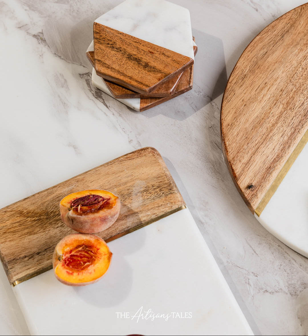 Marble cheese set with wooden accents displayed on a marble countertop alongside sliced peaches.