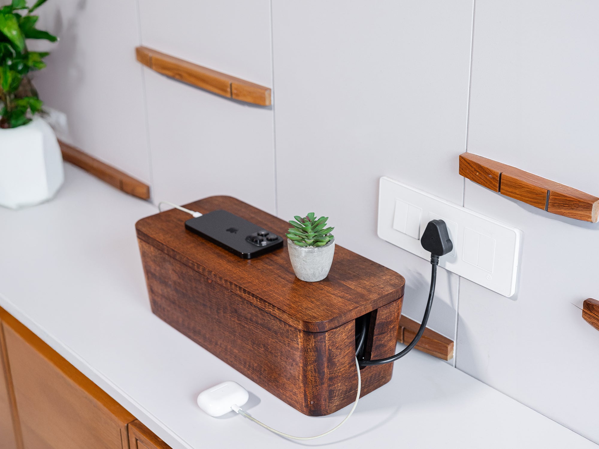 Mango Wood Cord Storage Box on a countertop with phone, charger, and small plant on top.