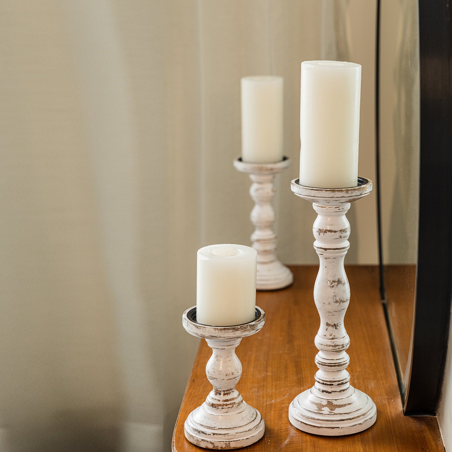 Rustic white wooden candle holders with pillar candles on a wooden surface.