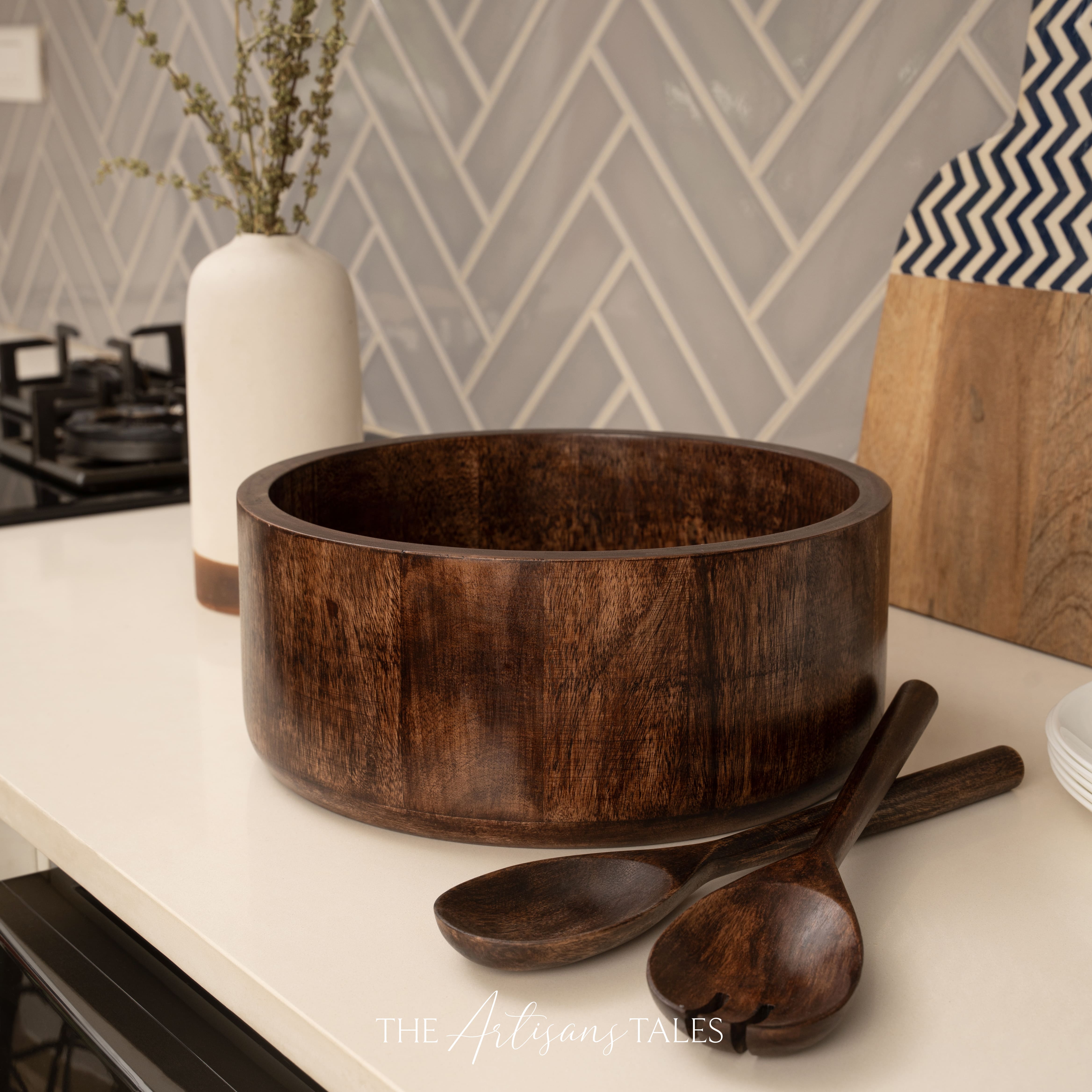 Wooden bowl and spoons on a kitchen counter with a geometric tile backsplash.