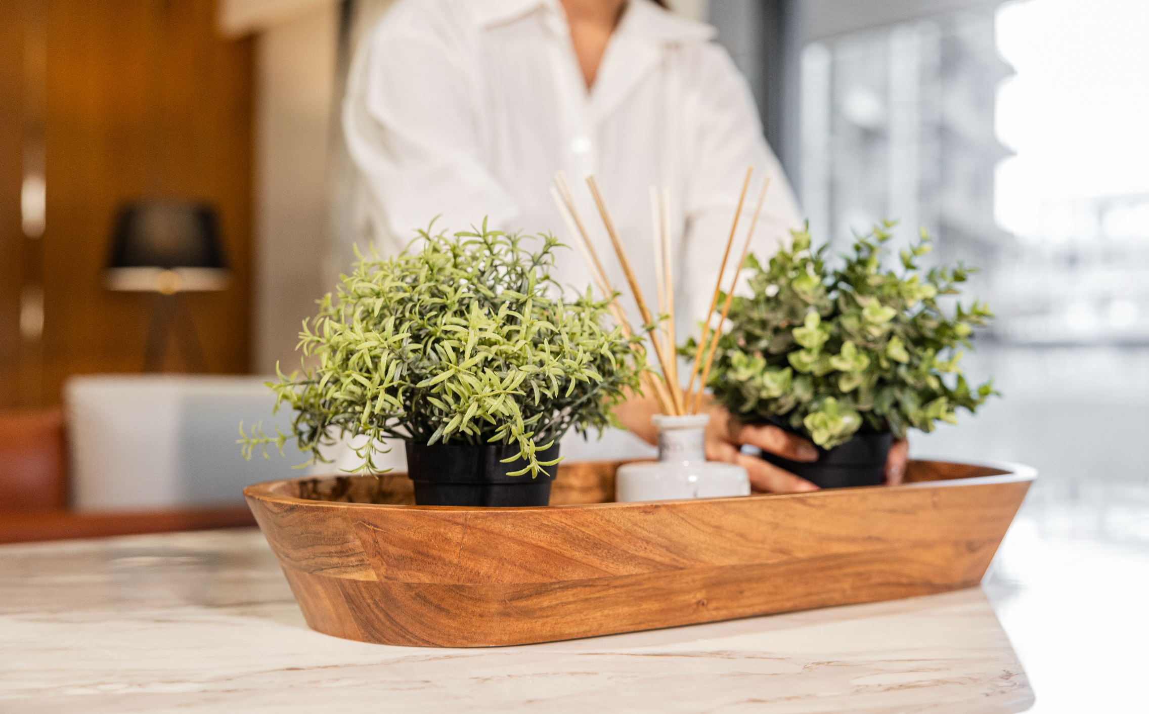 Acacia wood decorative tray holding artificial plants and a reed diffuser.