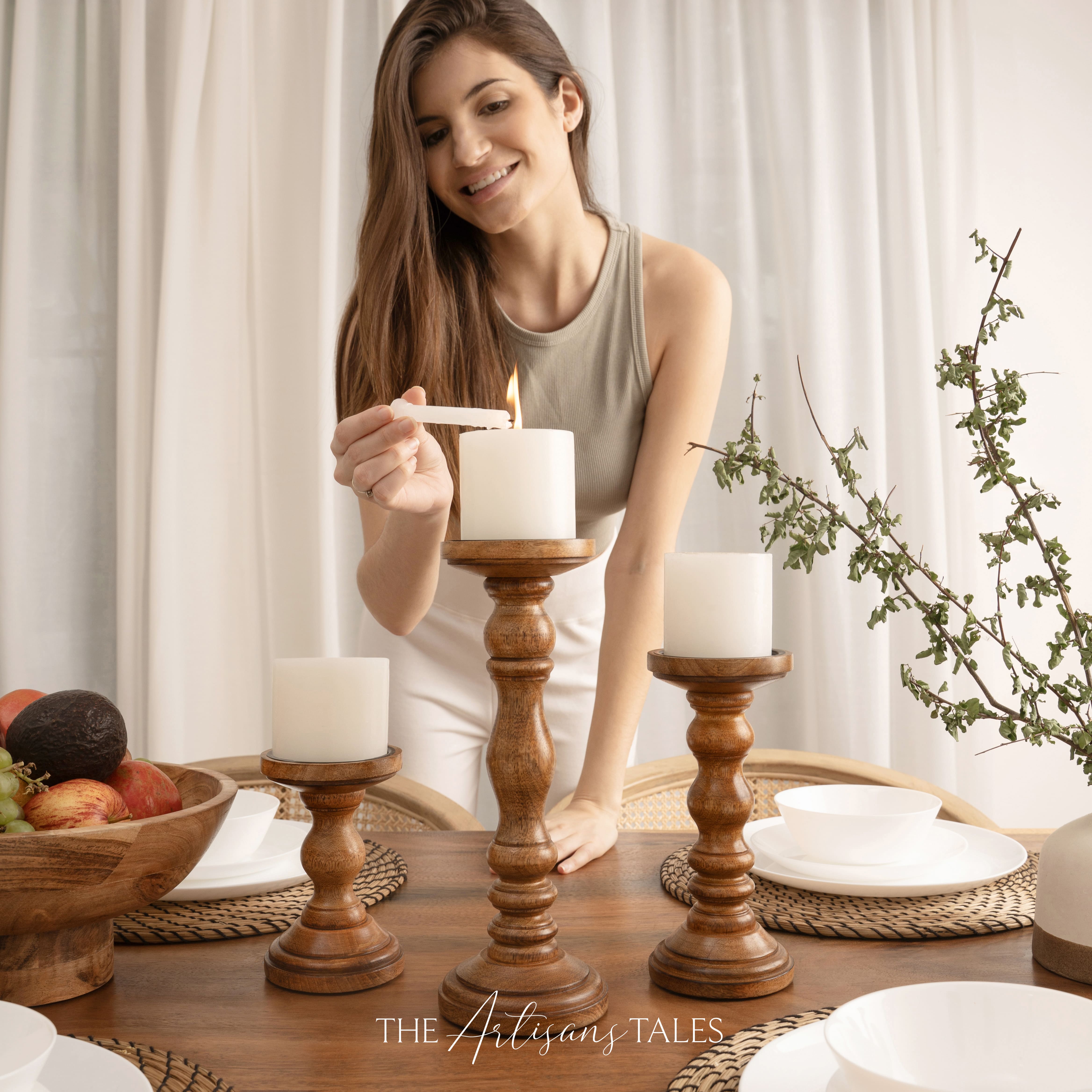 Woman lighting candles on wooden candlesticks