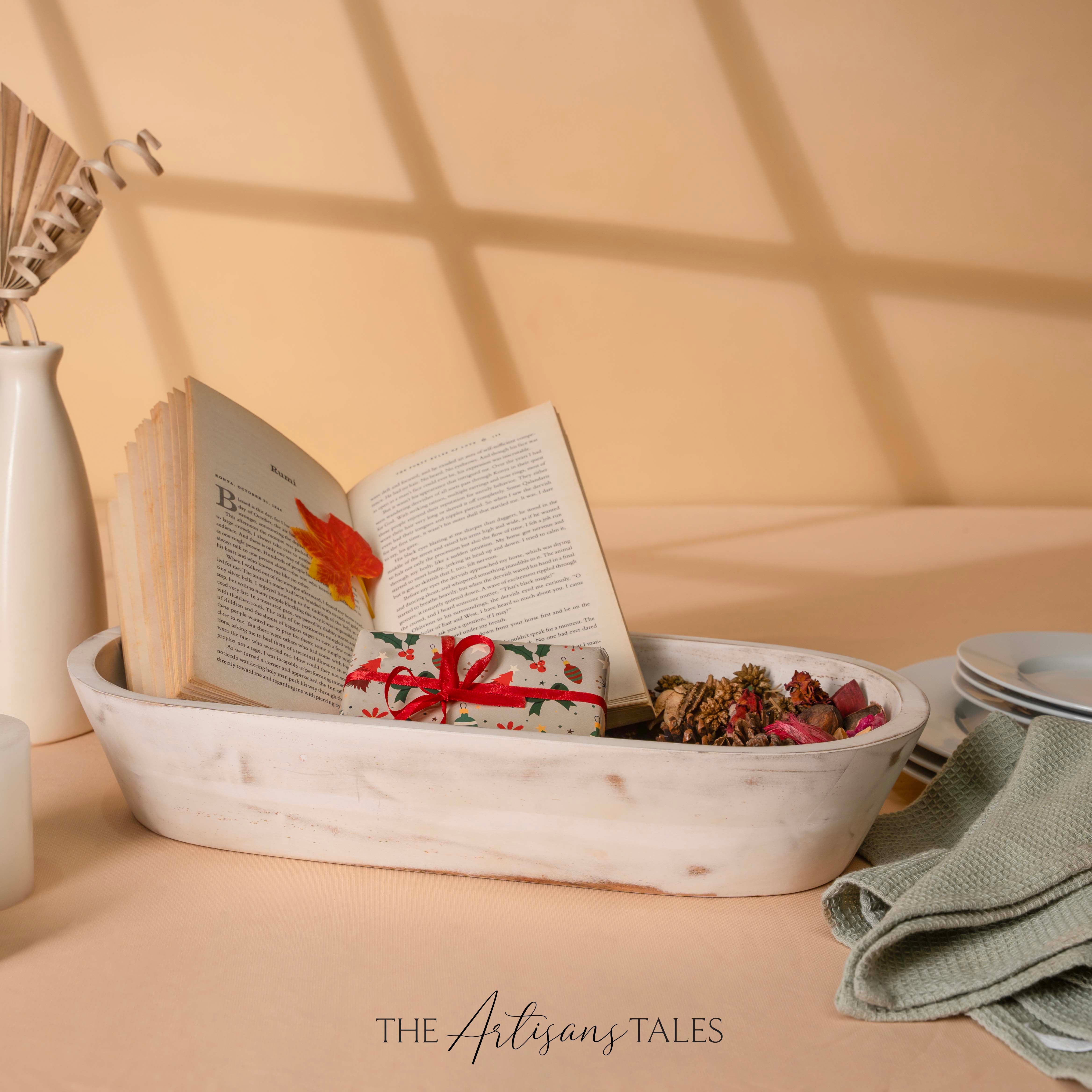 Open book with a gift wrapped in a decorative paper inside a white bow